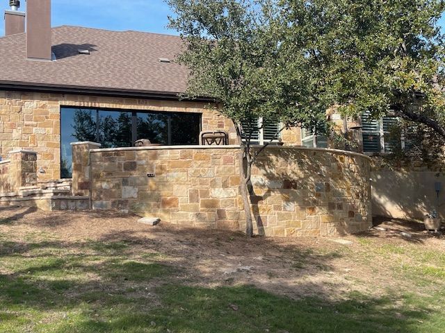 A large house with a stone wall and a tree in front of it.