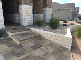 A brick walkway with steps and a stone wall in front of a house.