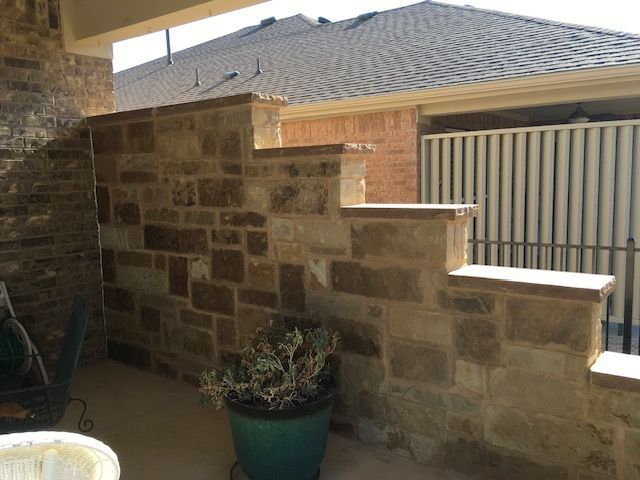 A potted plant is sitting on a patio next to a stone wall.