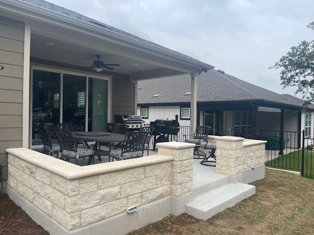A patio with a table and chairs on it in front of a house.