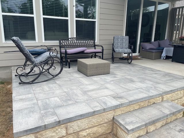 A patio with rocking chairs , a bench , and a table.