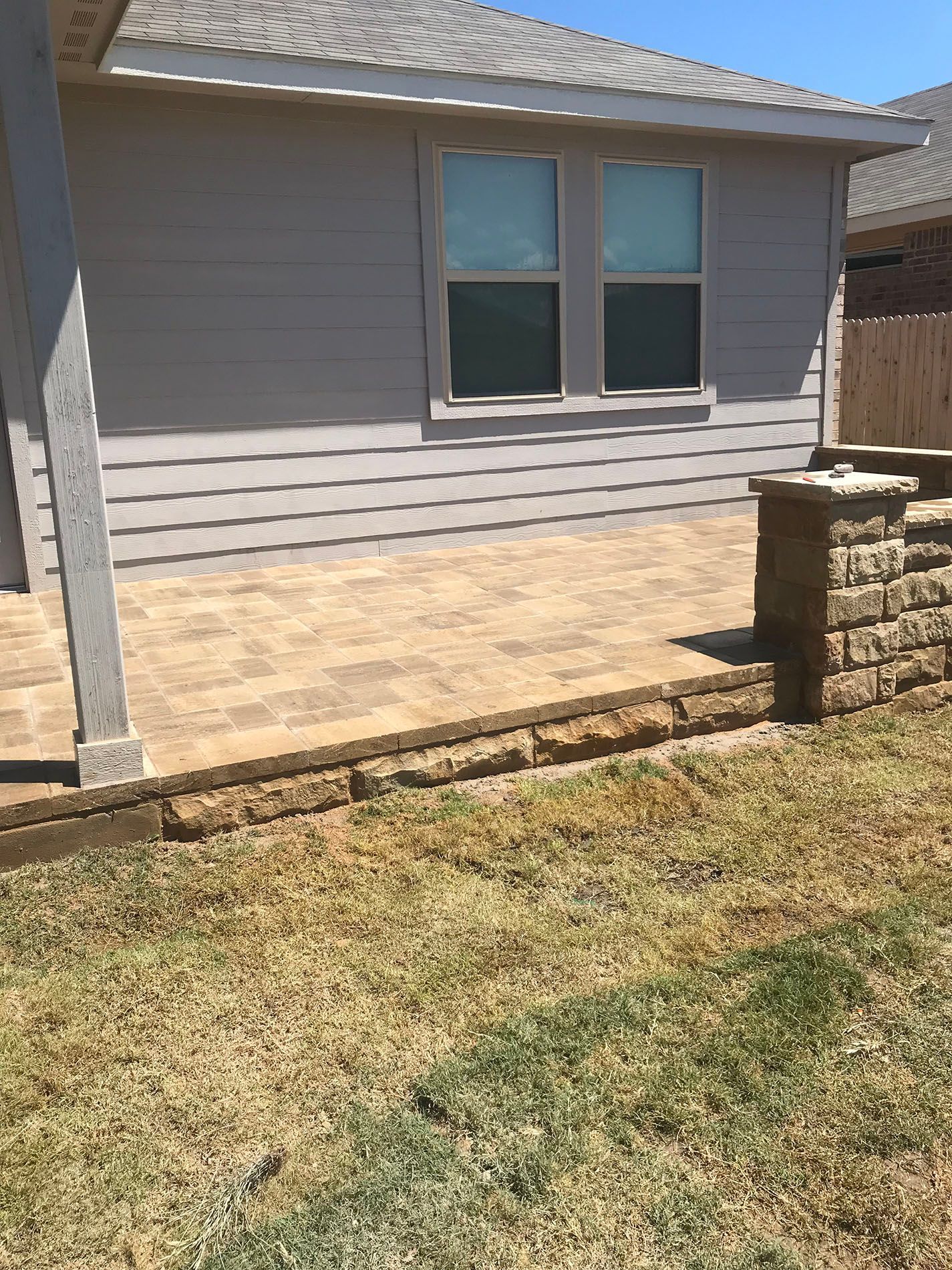 A house with a patio and a brick wall in front of it.