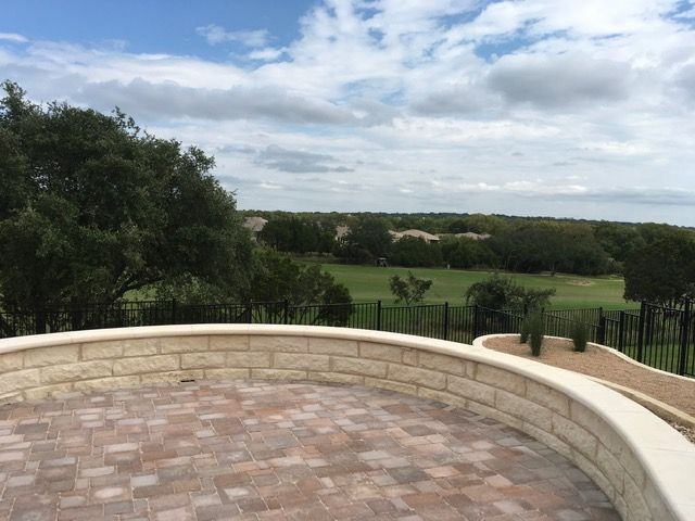 A brick wall with a view of a golf course and trees.