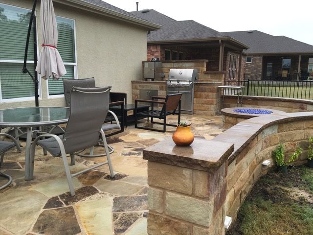 A patio with a table and chairs and a grill