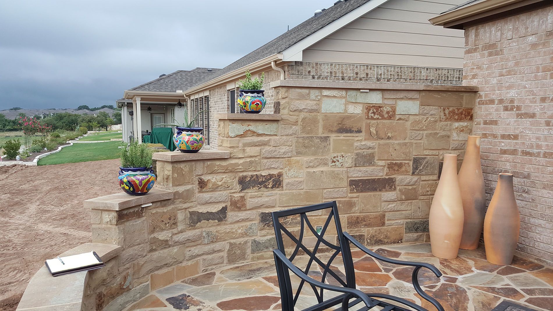 A chair is sitting on a stone patio next to a brick wall.