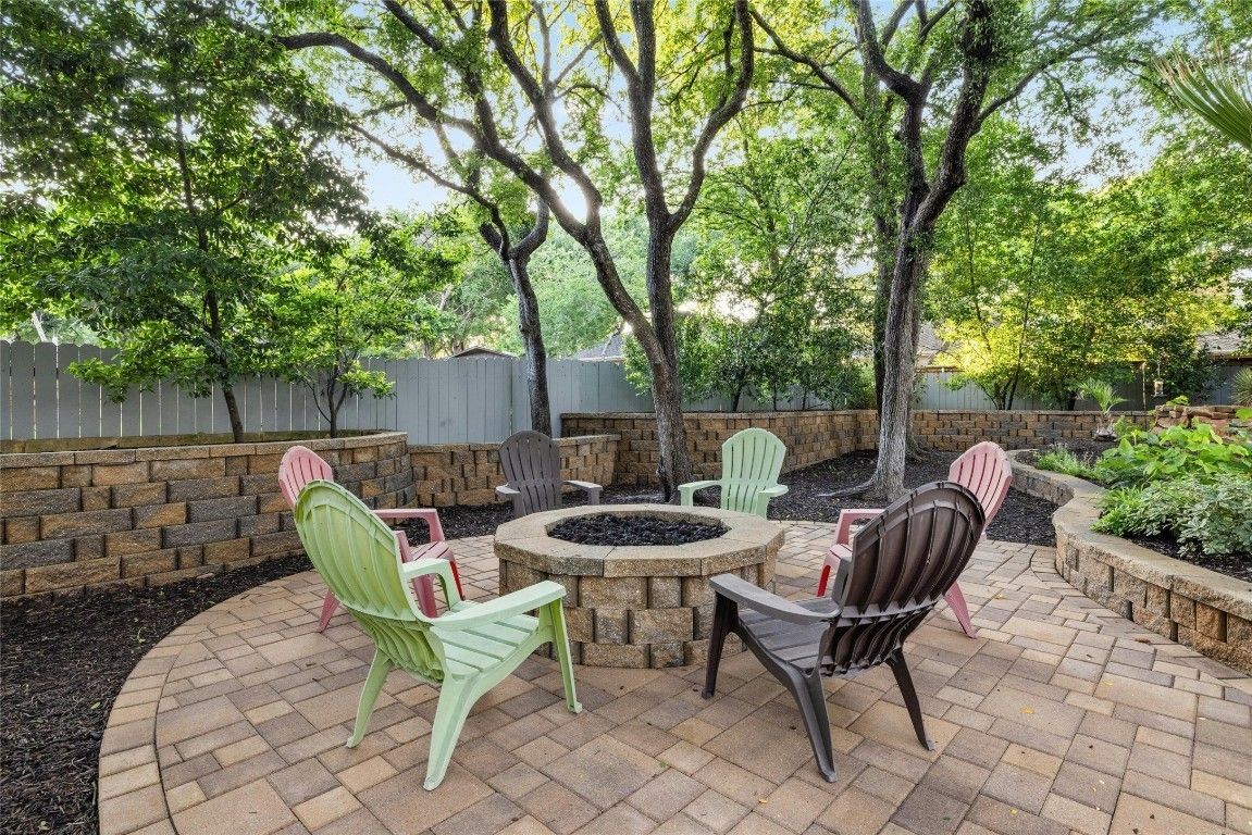 A group of chairs are sitting around a fire pit on a patio.