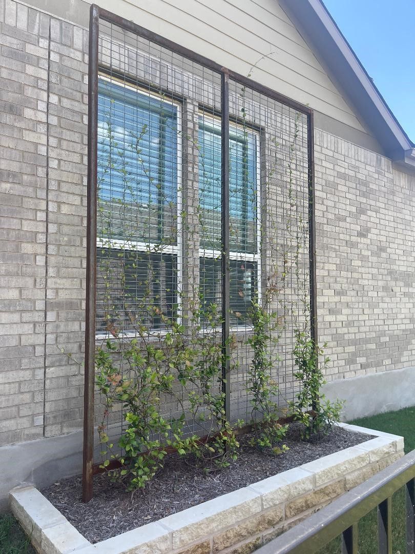 A brick house with a trellis in front of a window.