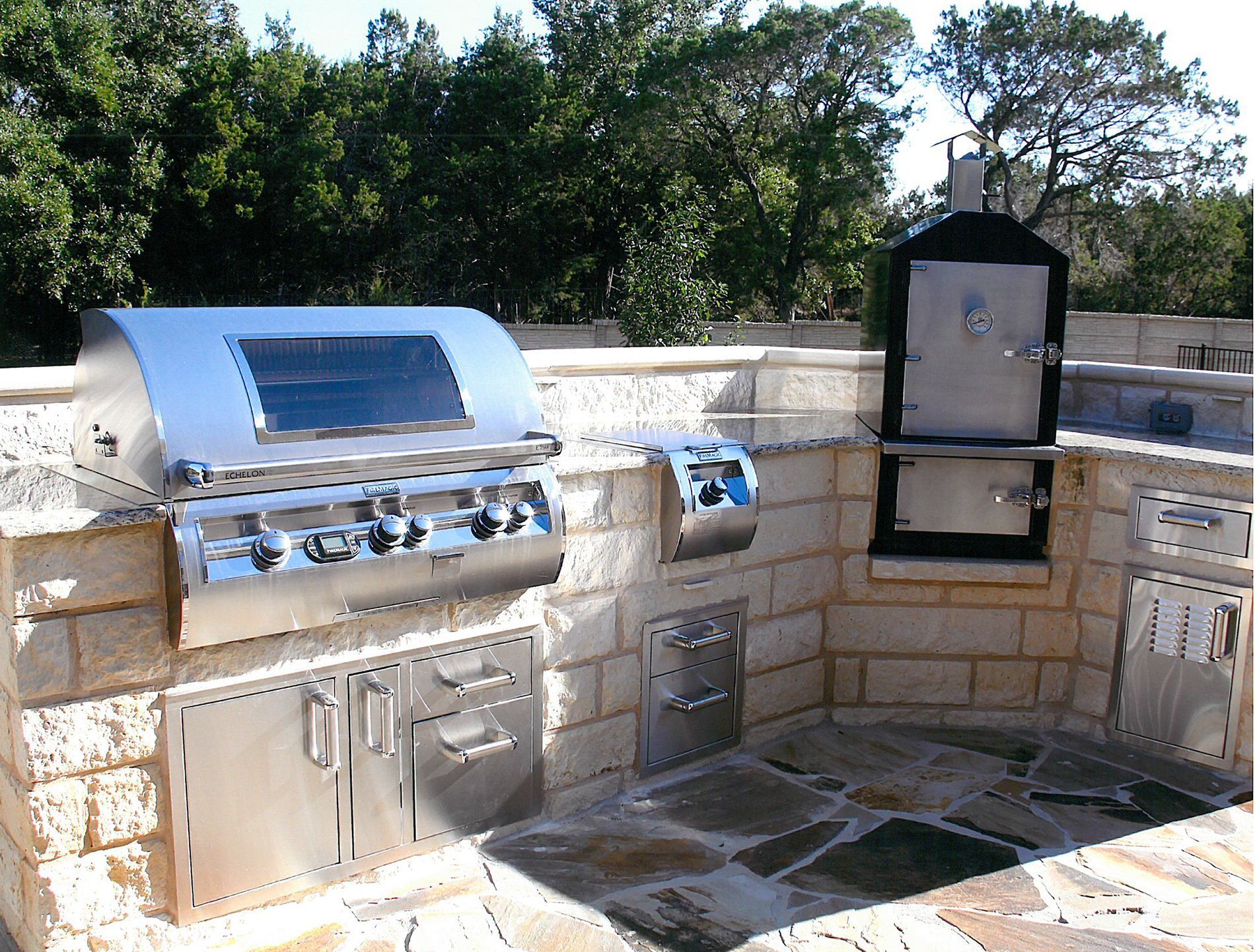 An outdoor kitchen with a stainless steel grill