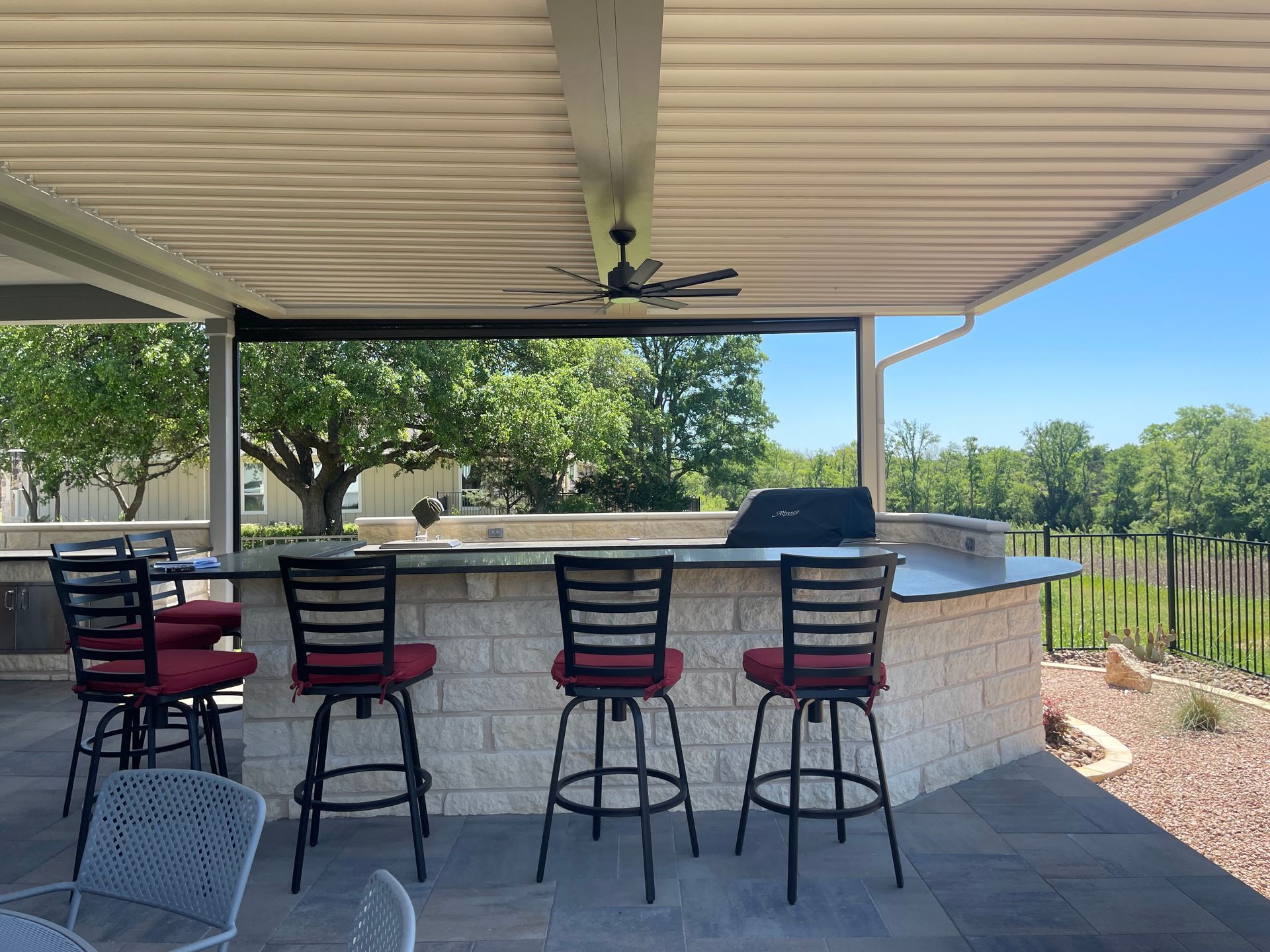 A patio with a bar and chairs under a roof.
