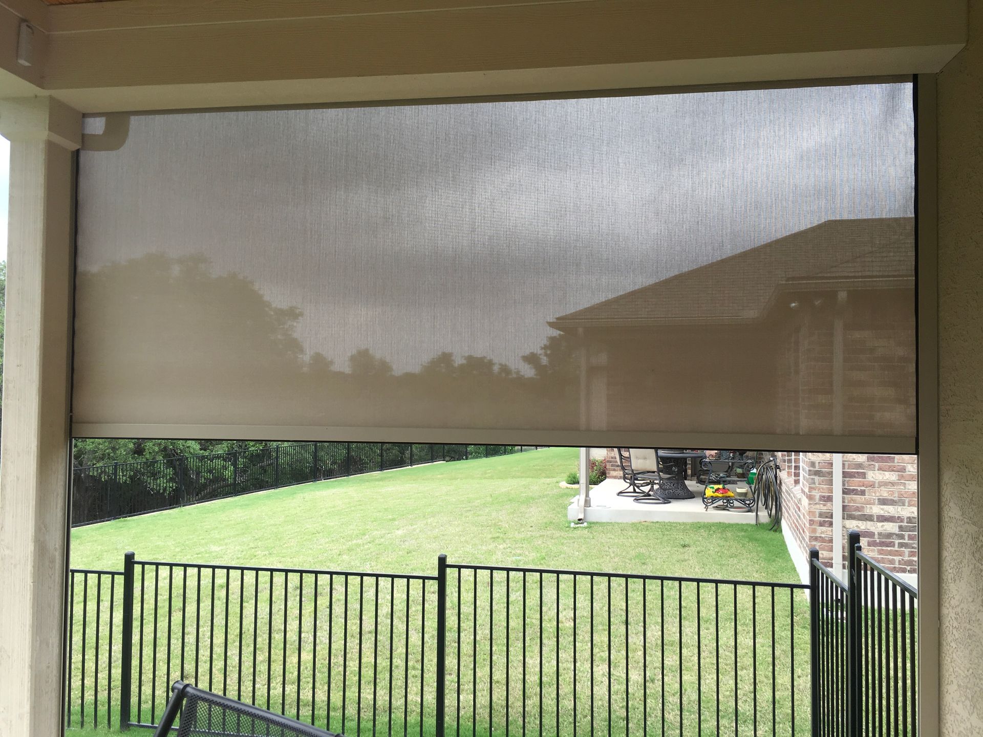 A screened in porch with a fence and a house in the background