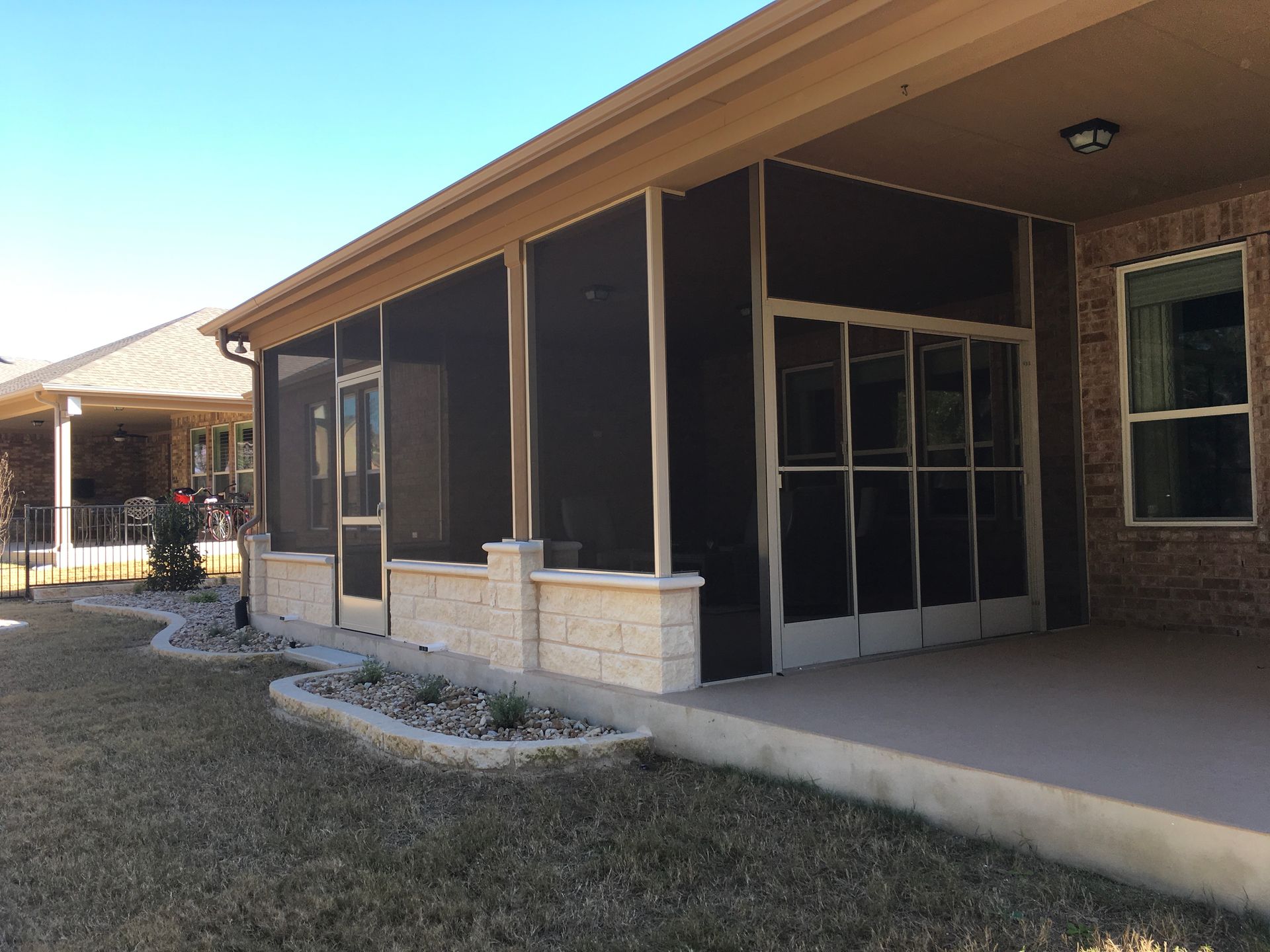 A screened in porch with a brick building in the background