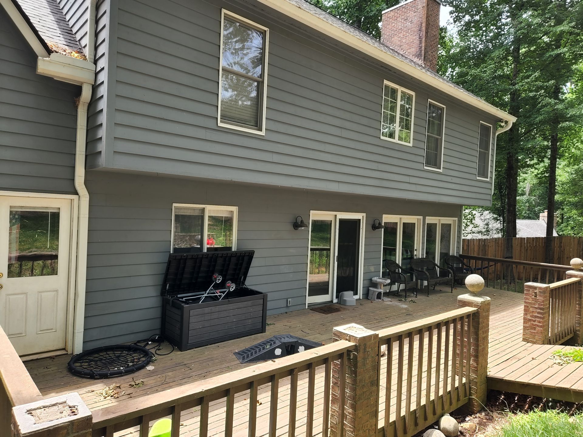 Gray house exterior with deck; doors and windows; black storage box on the deck.