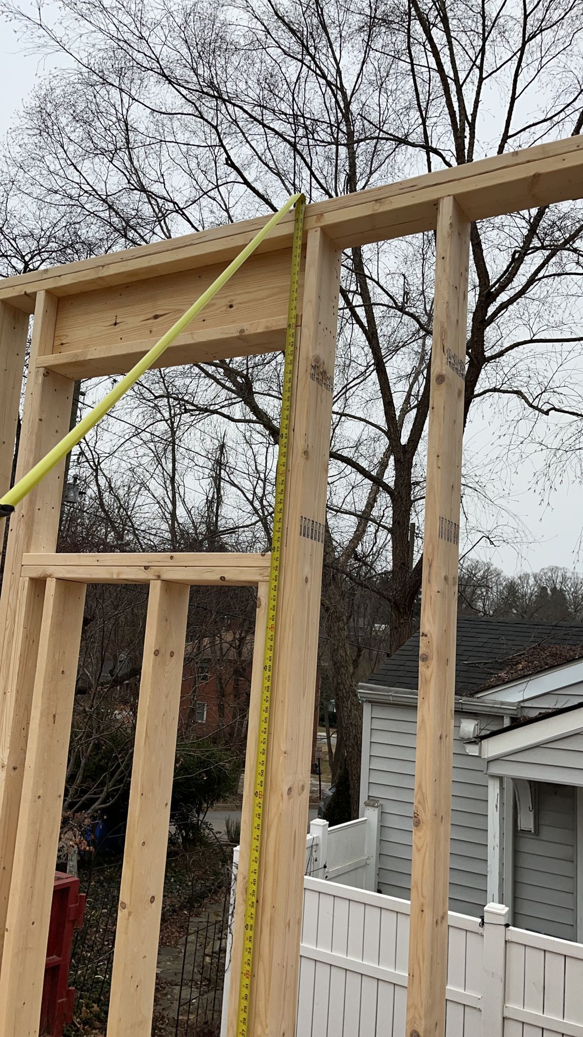 Framed wooden wall with a yellow tape measure.