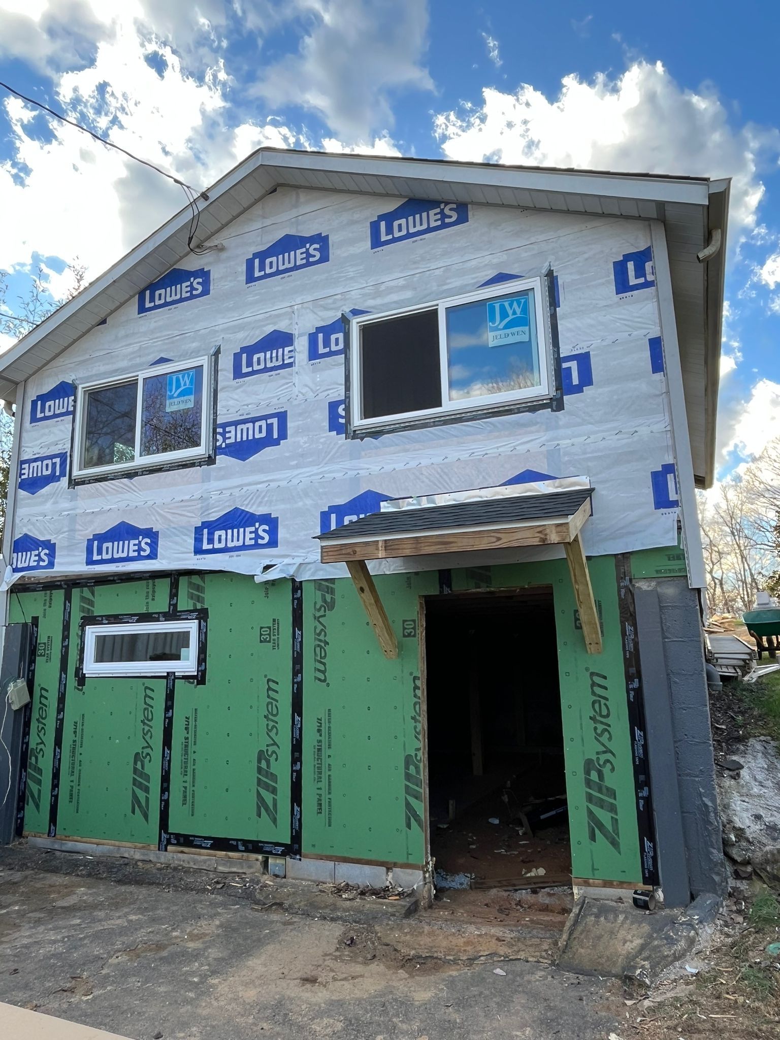 Two-story house under construction, exterior sheathing covered in blue Lowe's wrap and green Zip System panels.