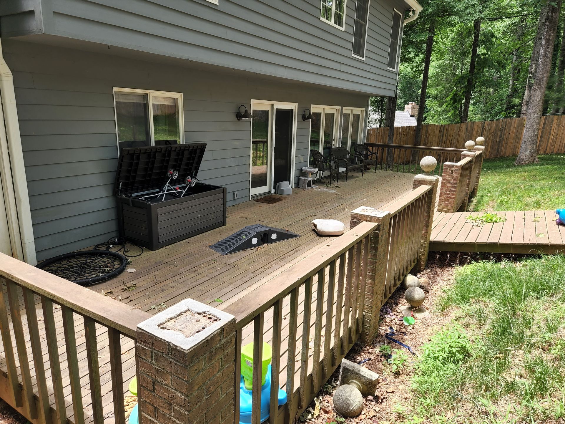 Backyard deck with composite railing, storage chest, and wooden walkway to grass.