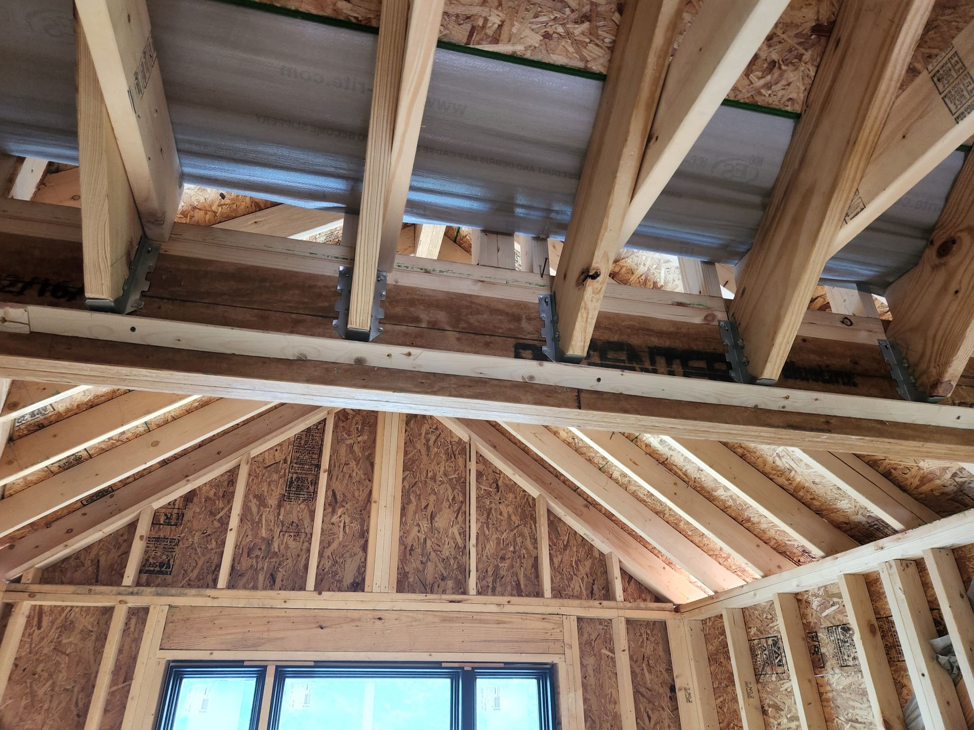 Interior view of a wooden home's framing under construction; the ceiling and walls are exposed.