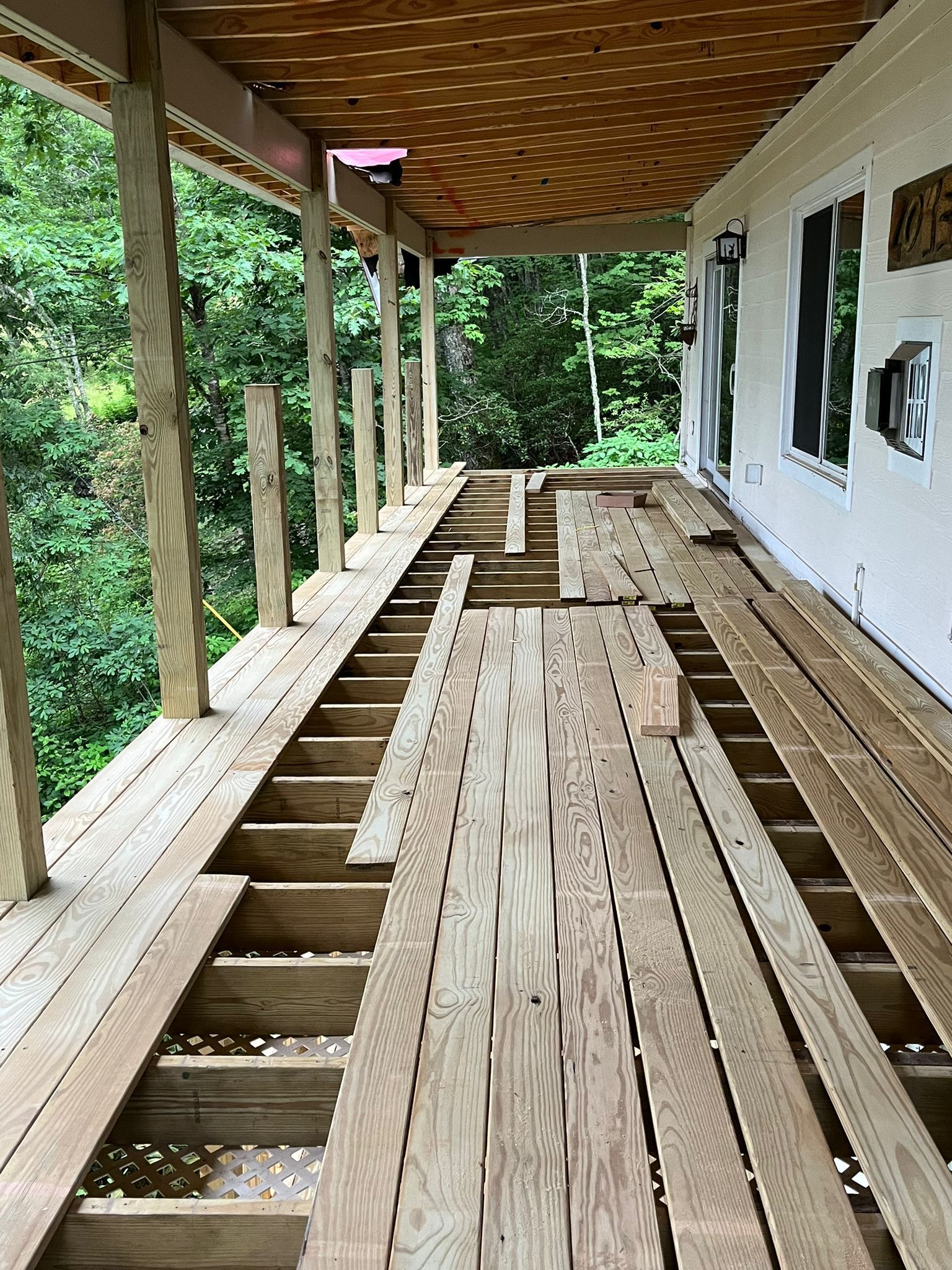 Deck under construction, missing planks, set against a forest background.