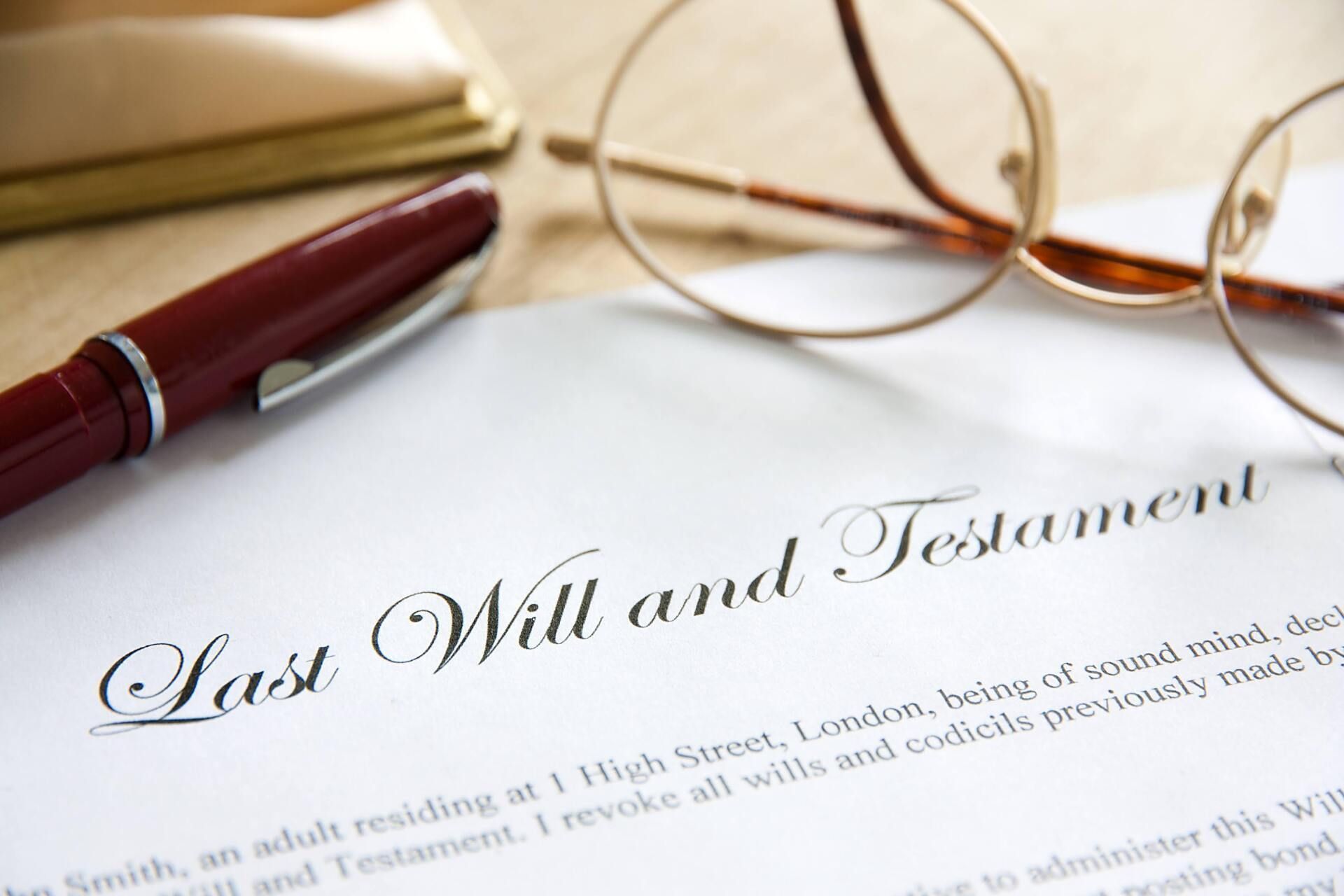 Last Will and Testament document with glasses and a pen on a table.