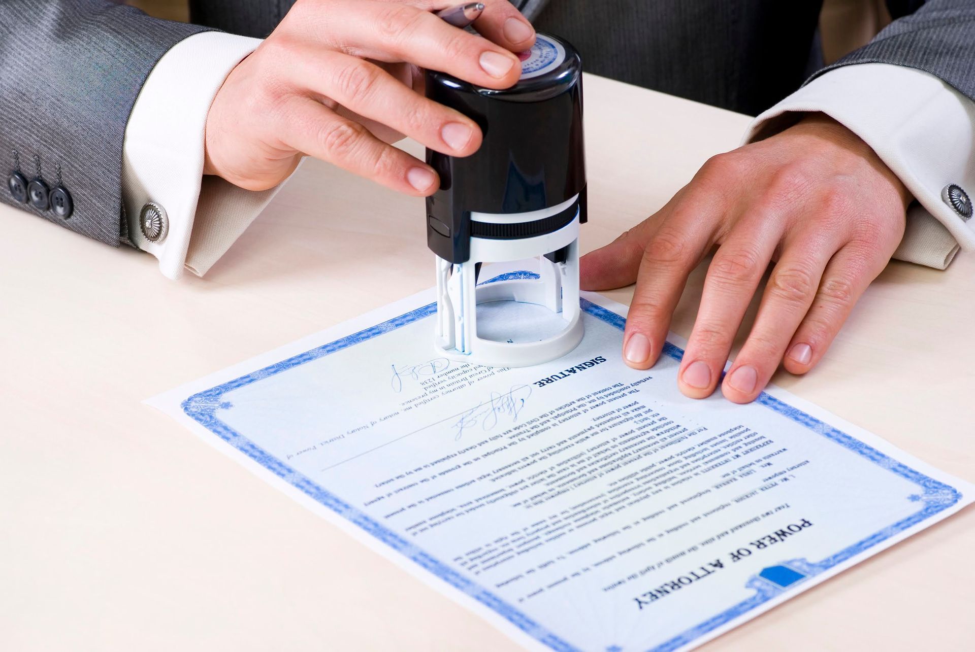 Person stamping a document with a rubber stamp on a light-colored surface.