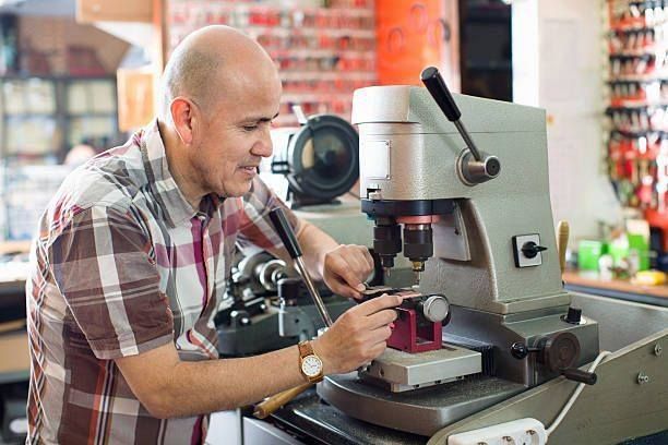 A man is using a machine to make keys in a locksmith shop.