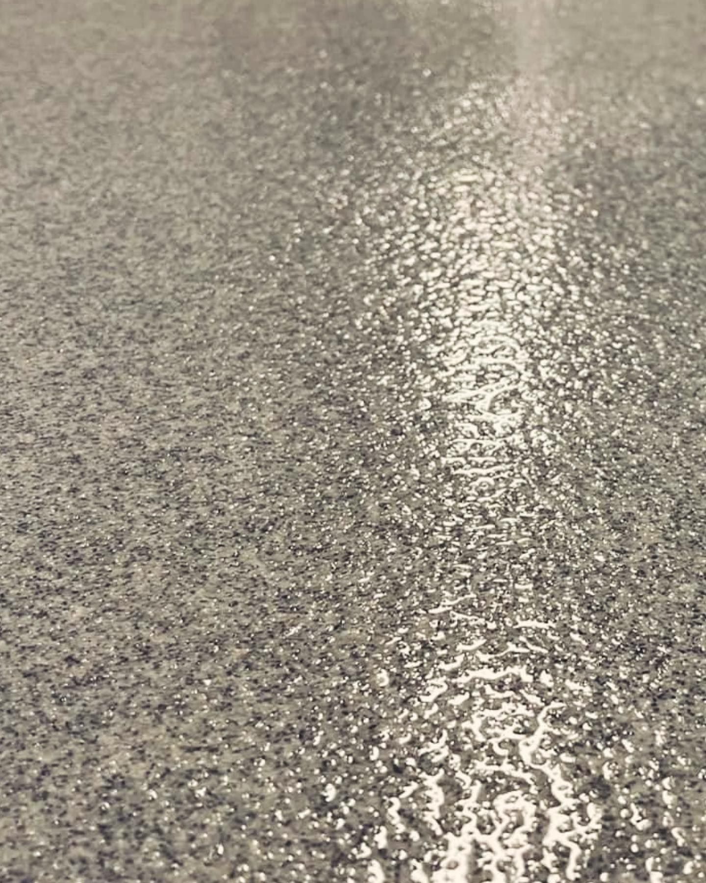 Textured gray and silver surface with a wet, glistening appearance.