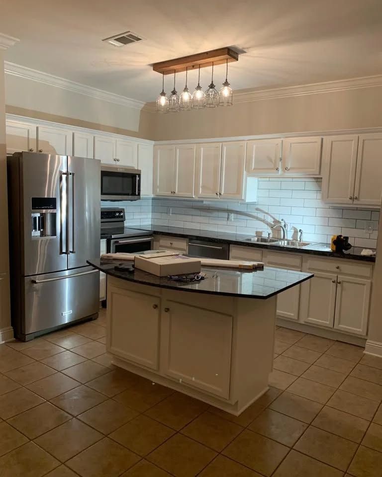 White kitchen with stainless steel appliances, black countertops, and a central island.