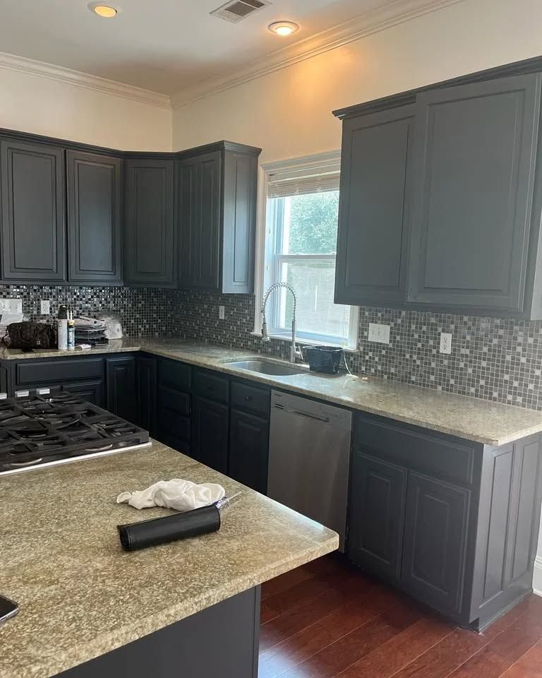 Kitchen with dark gray cabinets, light countertops, stainless steel appliances, and a window.