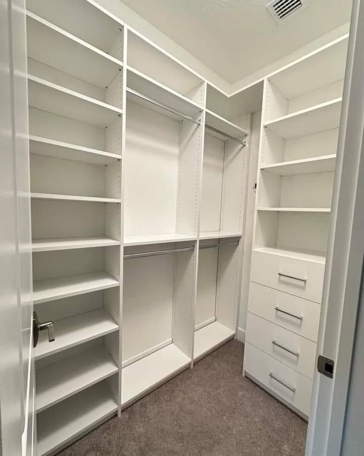 White, built-in closet with shelves, hanging rods, and drawers. Empty and ready for use, room with carpet flooring.