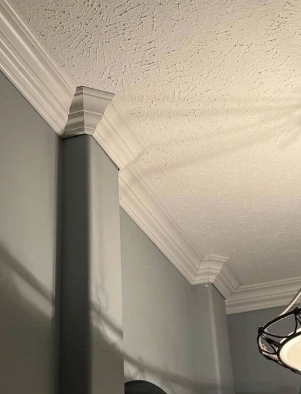 White crown molding meets a corner on gray walls and textured ceiling.