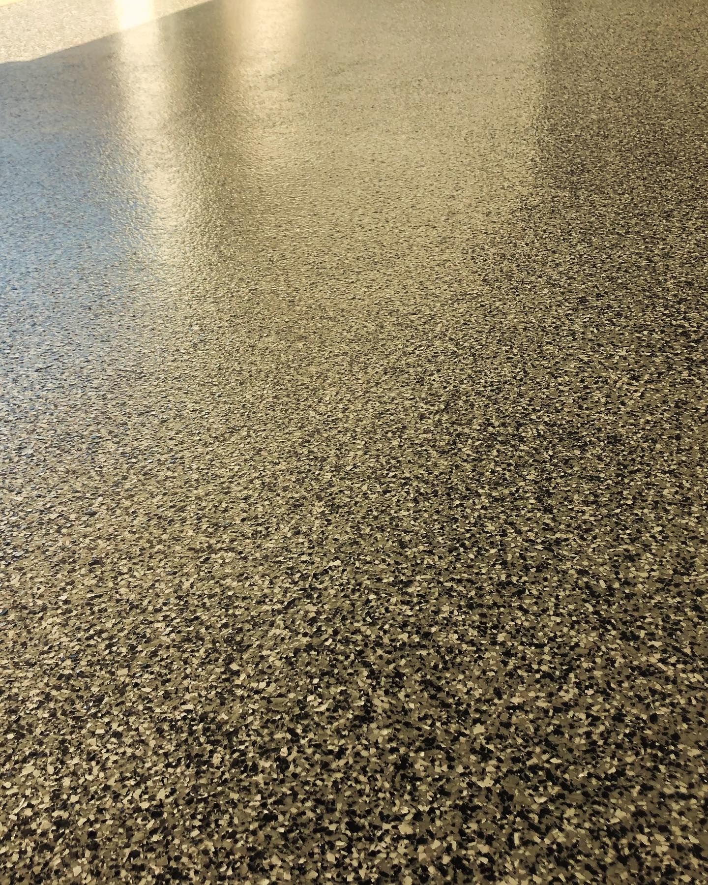 Granular, speckled flooring in shades of gray and beige, reflecting light.