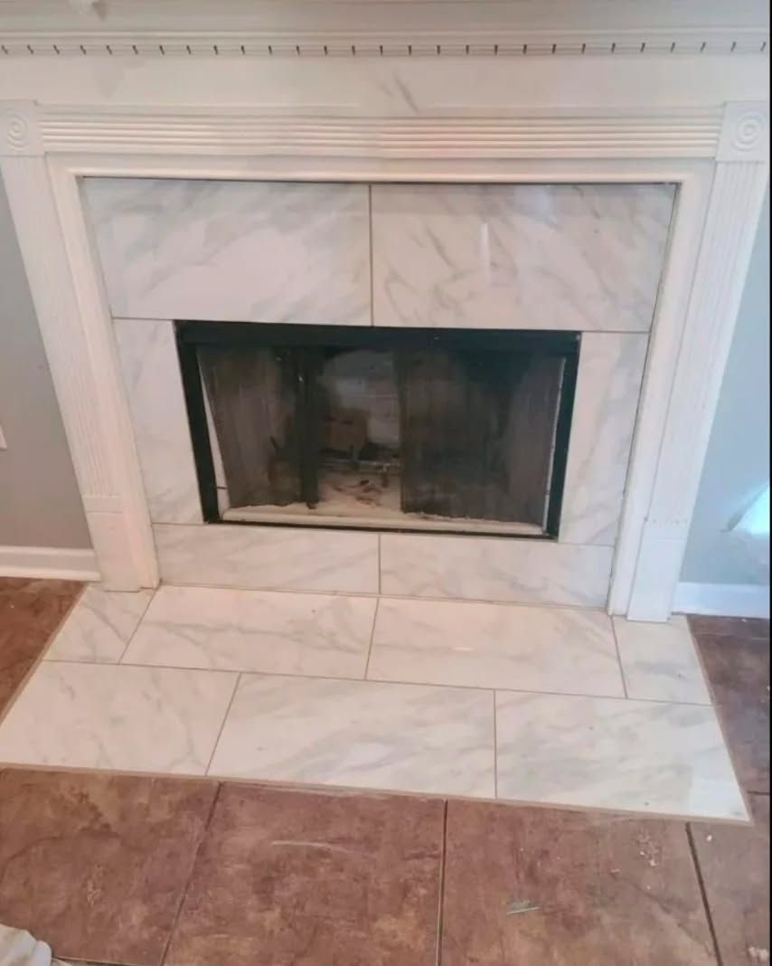 White marble tiled fireplace with dark firebox and white trim.