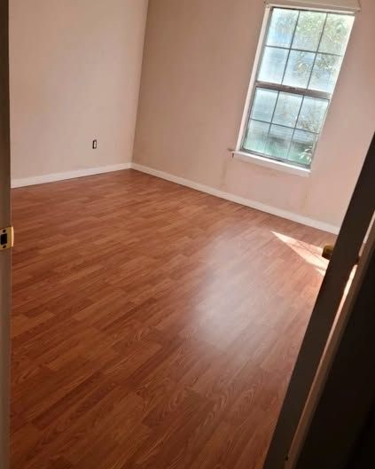 Empty room with laminate flooring, a window, and light pink walls.