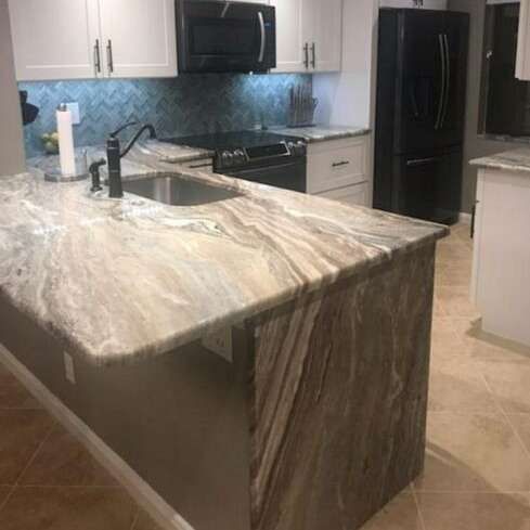 Kitchen with a marble countertop island and black appliances.