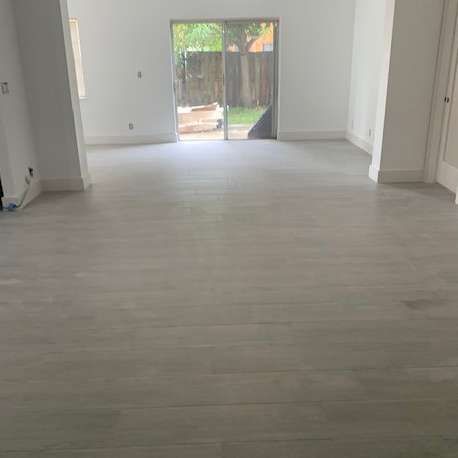 Empty room with pale wood floors, sliding glass door, and white walls.