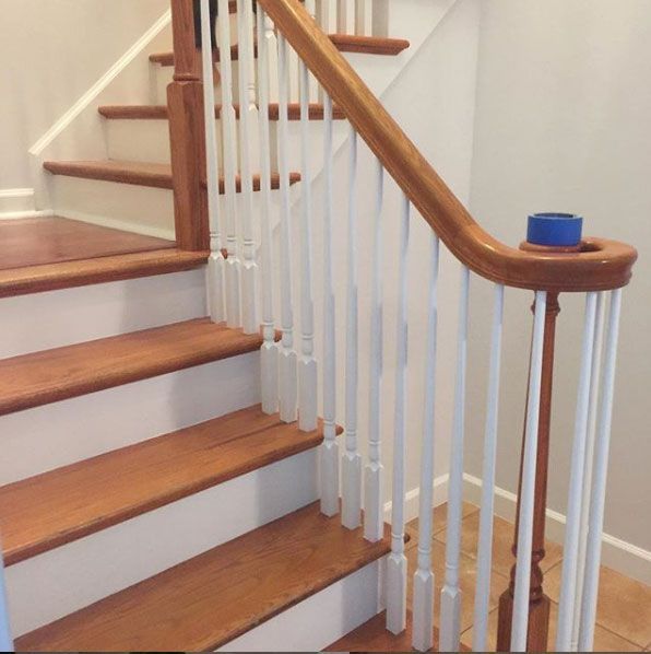 Wooden staircase with white spindles, brown handrail, and wooden steps.