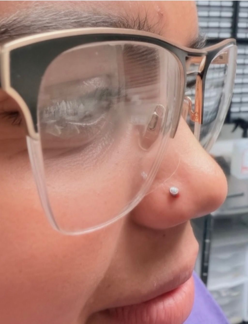Close-up of a person's profile wearing glasses with a nose stud.