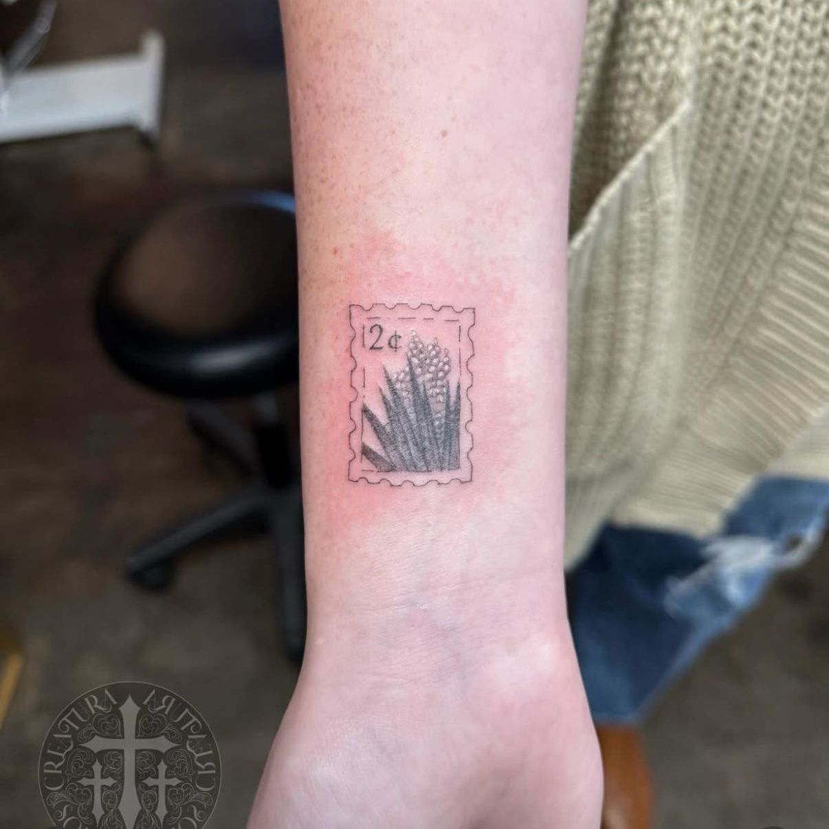 A person has a tattoo of a stamp with the number 12 on it