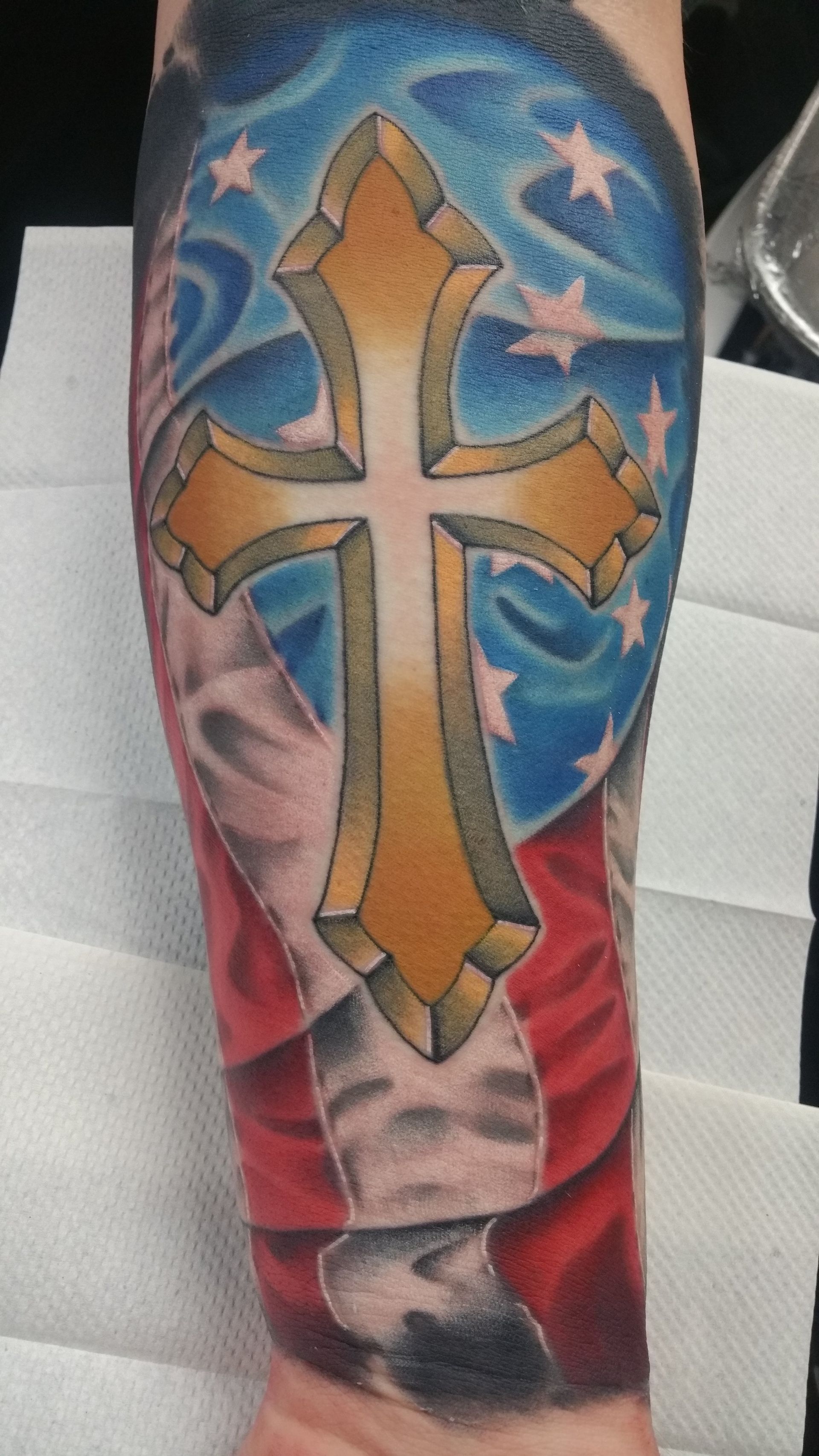 A tattoo of an american flag with a cross on it