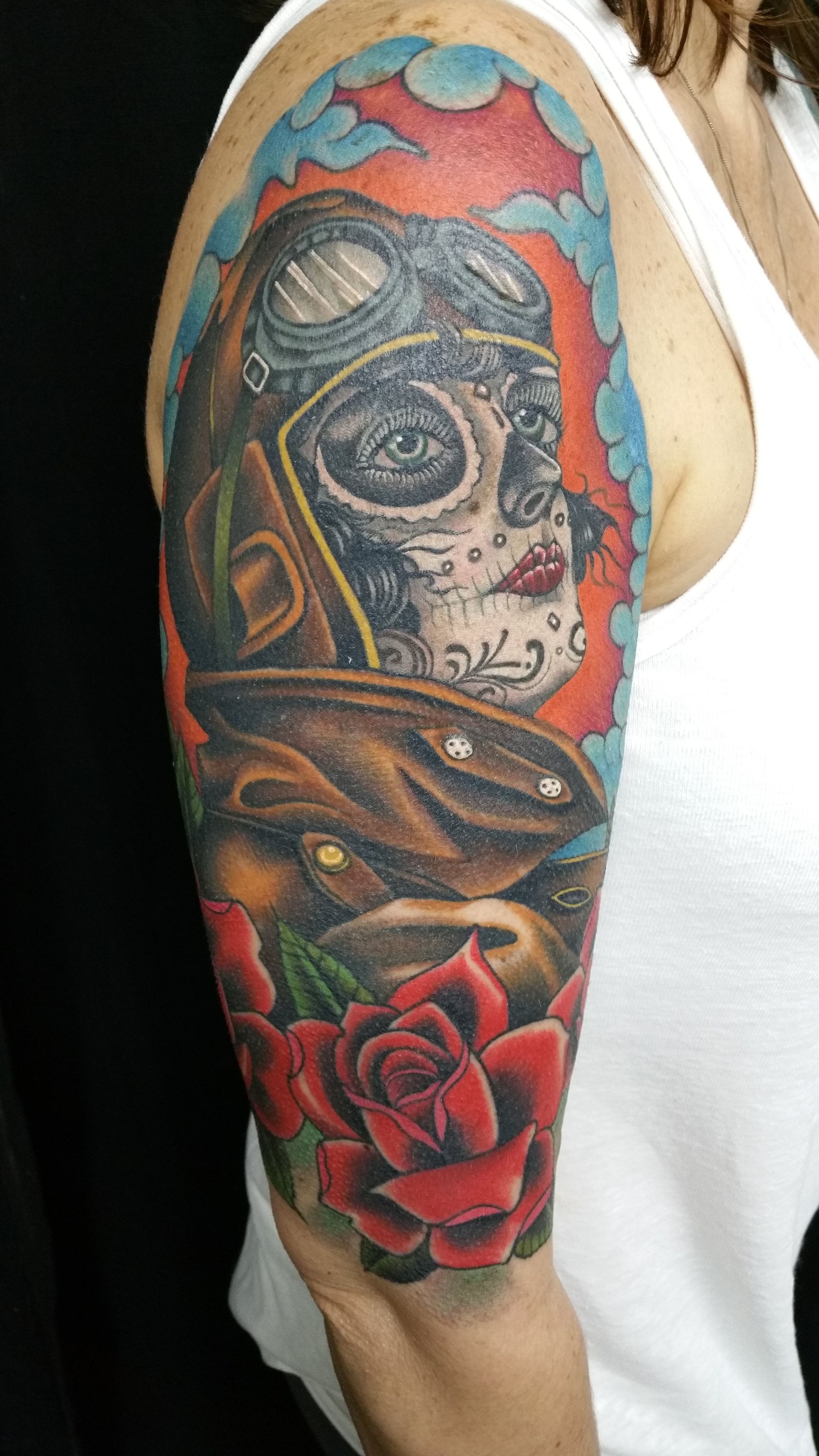 A man has a tattoo of a woman that reflects Mexican culture, with roses surrounding her.