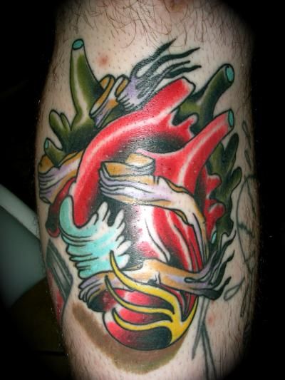 A man has a colorful tattoo of a heart on his leg