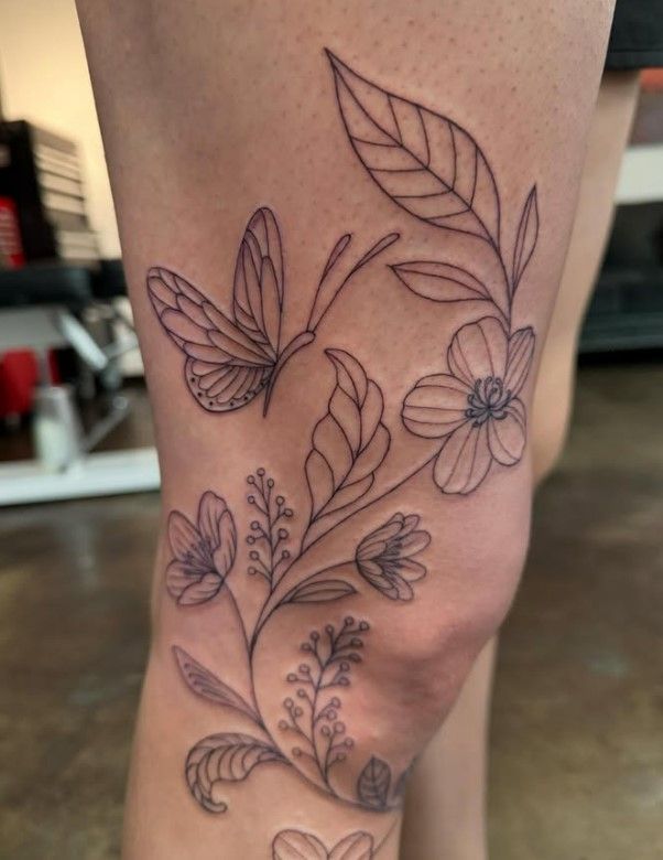 A woman has a tattoo of butterflies and flowers on her leg