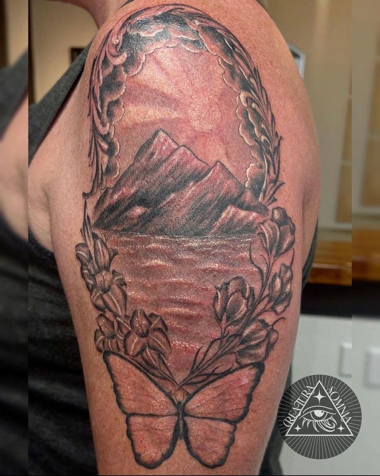 A woman has a tattoo of a butterfly and mountains on her arm