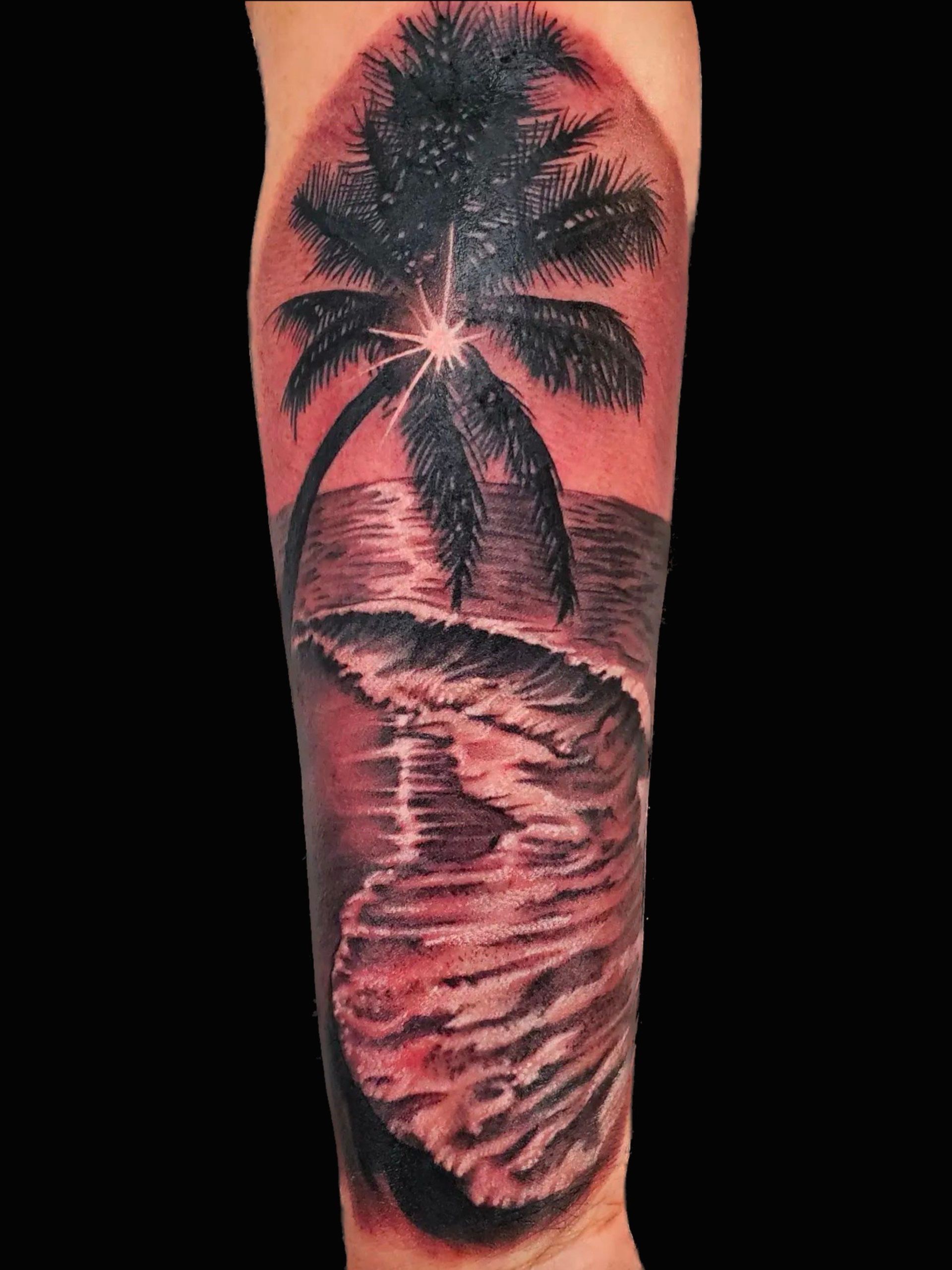 A tattoo of a palm tree and waves on a beach