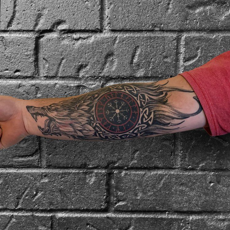 A person with a tattoo on their arm against a brick wall.