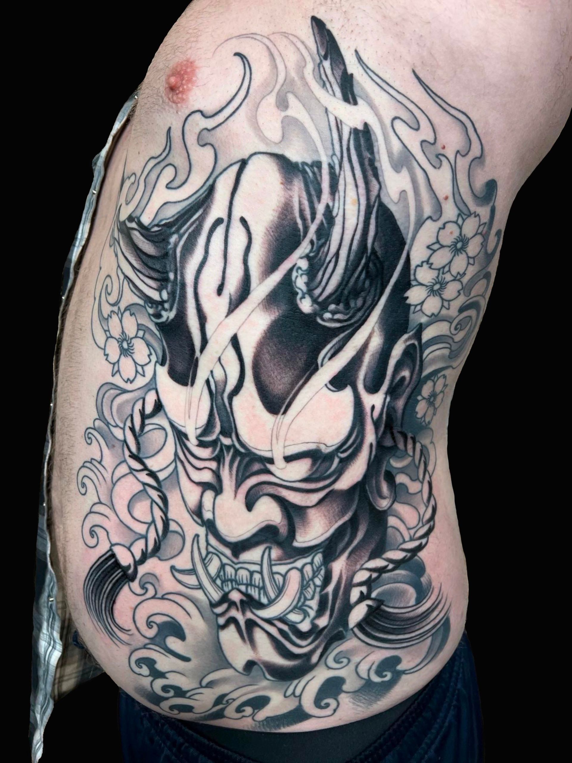 A man has a tattoo of a demon on his side.