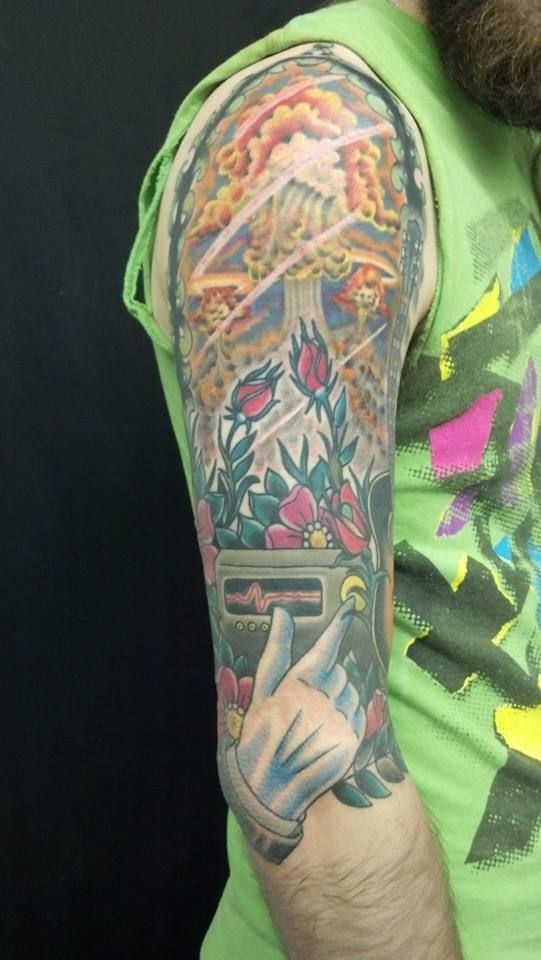 A man in a green shirt has a tattoo on his arm.