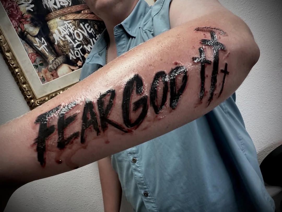 A person has a tattoo on their arm that says fear god