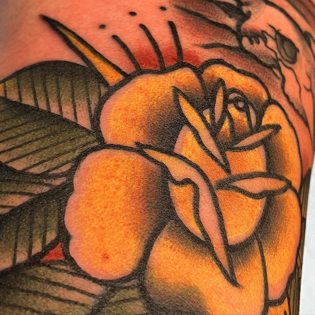 A close up of a tattoo of a yellow rose