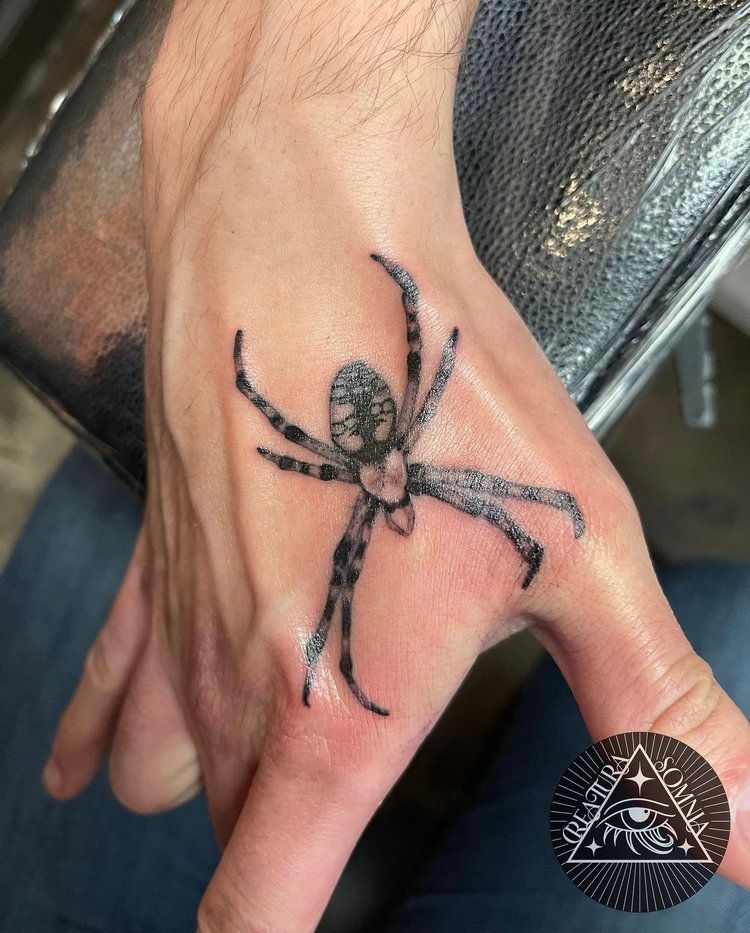 A person has a tattoo of a spider on their hand