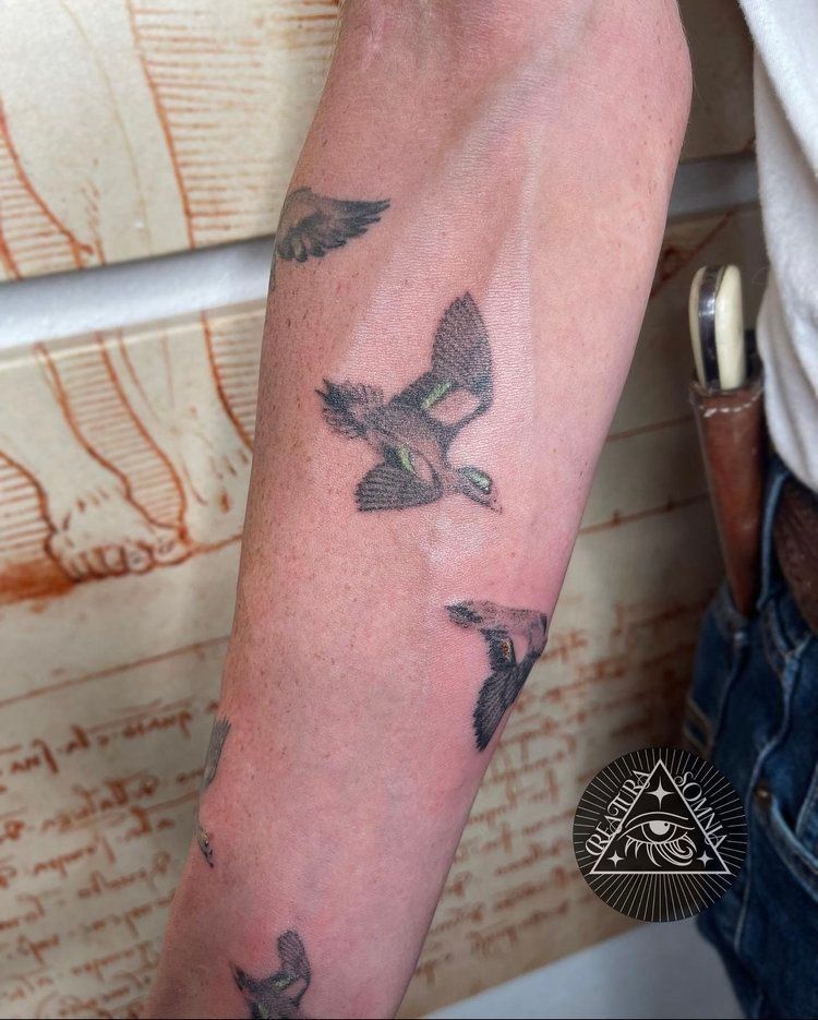 A person has a tattoo of birds on their forearm